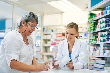 A pharmacist helps out an elderly woman at a pharmacy. 