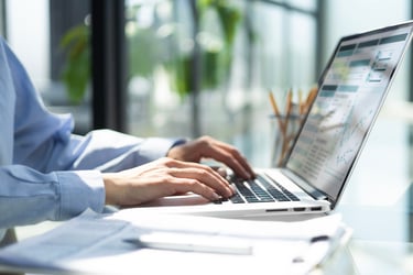 A female employee analyzing healthcare data on laptop screen in hybrid office setting.
