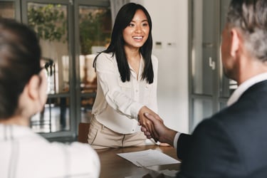 A woman shaking hands with a job interviewer in a modern office. 