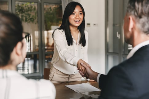 A woman shaking hands with a job interviewer in a modern office. 