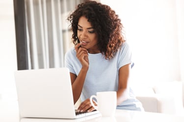 A person seated at a kitchen counter using a laptop to research quality in healthcare.