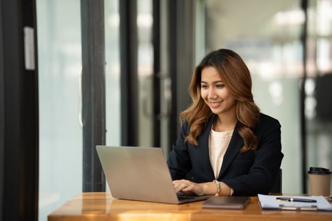 A business woman uses Bluebook Comply on a laptop while sitting in an office. 