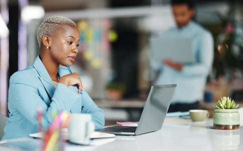 A woman looks at a laptop while sitting in an office. 