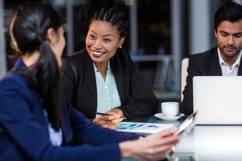 Coworkers smiling and talking in an office during a meeting. 