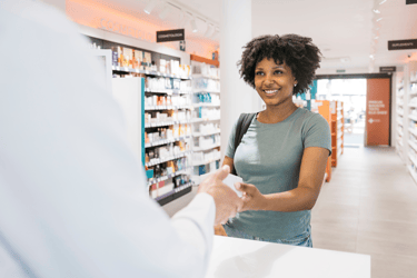 Pharmacist handing over medicine to customer in drugstore.
