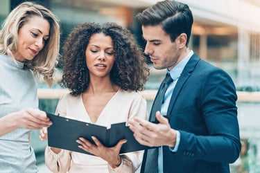 Three employees review compliance information together. 
