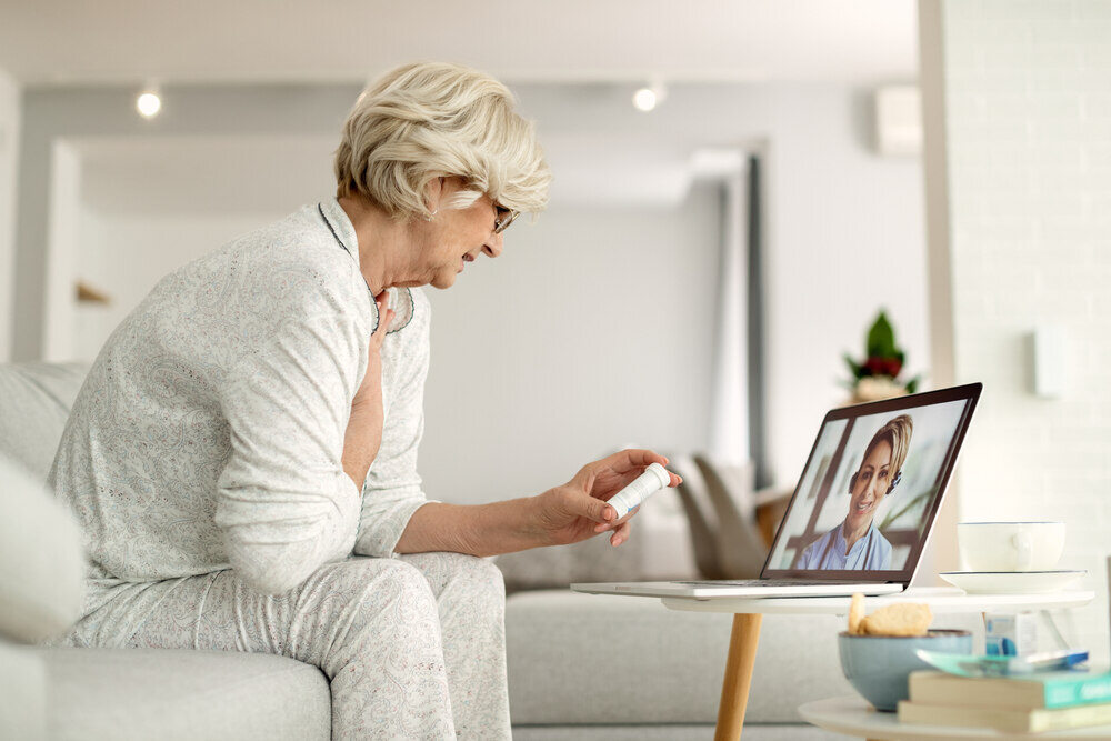 An older woman uses telehealth services on a laptop. 