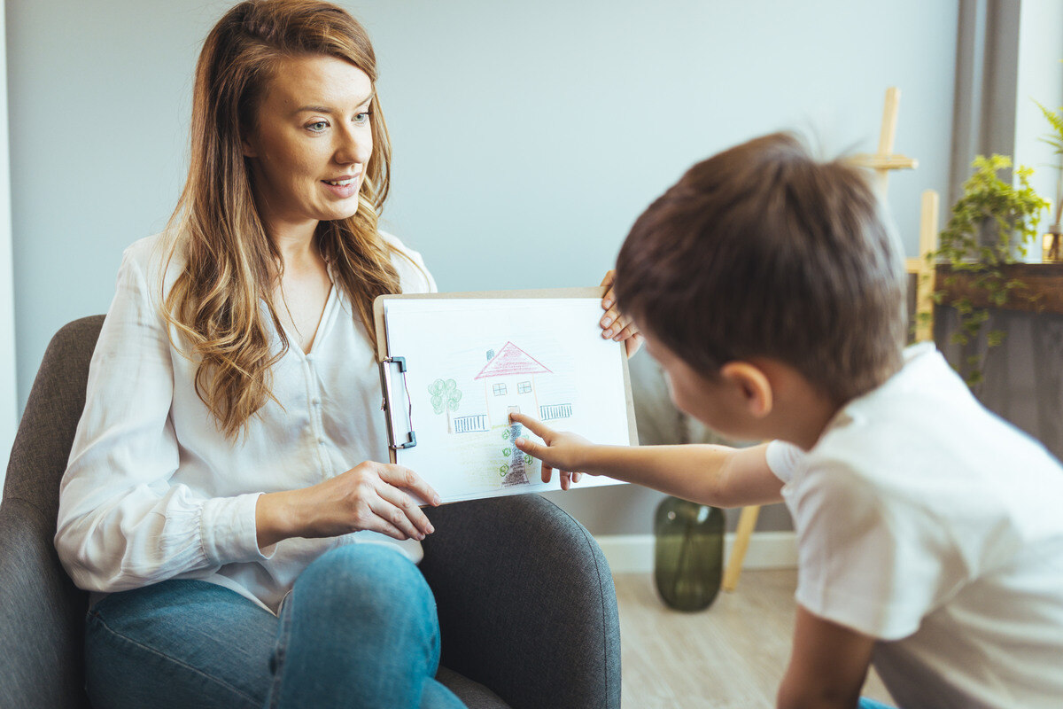 A female child psychologist working with an autistic child in an office. 