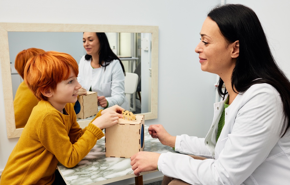 Female psychologist using ABA therapy techniques with a child patient.